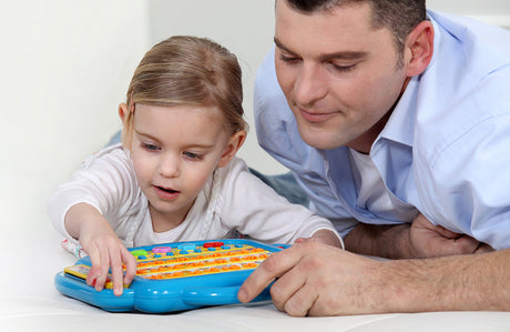 Vater und Tochter spielen mit elektronischem Spielzeug.