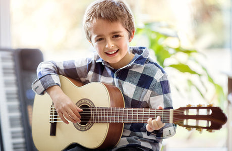 Junge spielt Akustikgitarre.