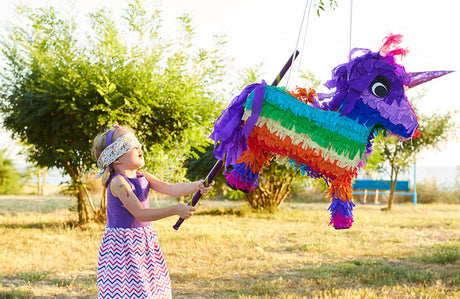 Mädchen schlägt eine Pinata mit einem Stock.