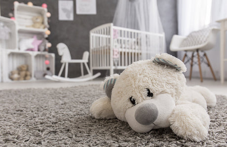 Ein niedlicher Teddy liegt im Kinderzimmer auf einem Teppich.